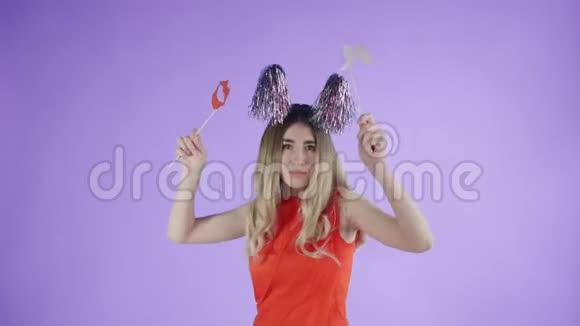 戴着派对帽的漂亮女孩正在紫色背景下飘落的纸屑和气球下跳舞视频的预览图