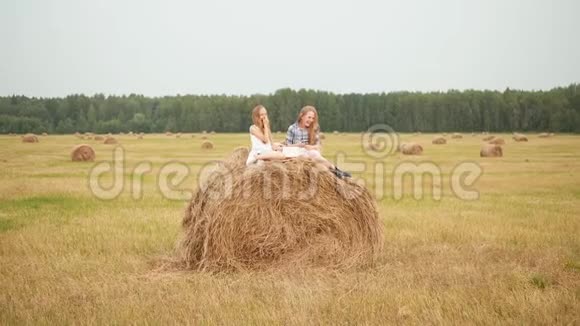 可爱的快乐女孩书坐在田野的干草堆上视频的预览图