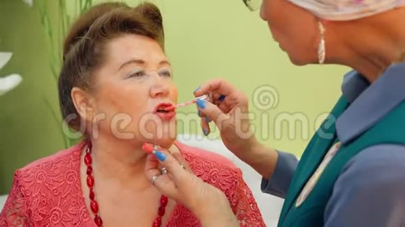 一位年长的妇女正她的朋友的嘴唇上涂上唇彩视频的预览图