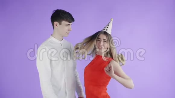 年轻的女人和男人在紫色的背景下在五颜六色的纸屑下跳舞视频的预览图