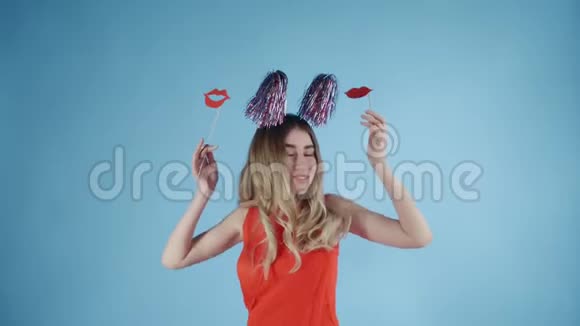 戴着派对帽的漂亮女孩在蓝色背景下飘落的肥皂泡下跳舞视频的预览图