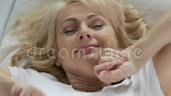 老妇人躺在床上睡后伸懒腰微笑着俯视图视频的预览图
