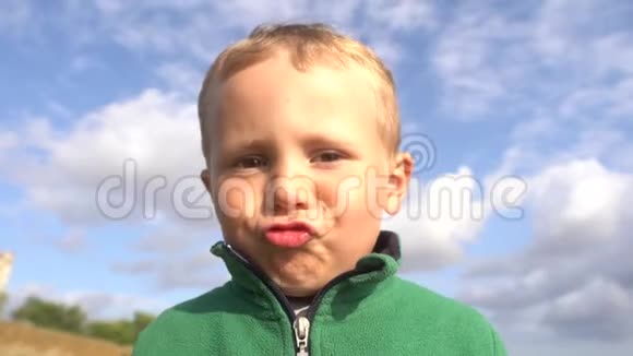 特写小男孩做嘴唇鸭子真实的情感天空中的男孩视频的预览图
