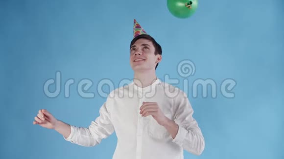 戴着派对帽的年轻人在蓝色背景下的气球下跳舞视频的预览图