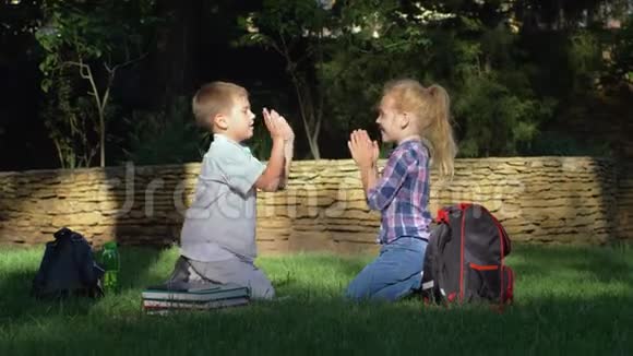 快乐的男生和女生在放学后坐在公园里玩拍手游戏视频的预览图
