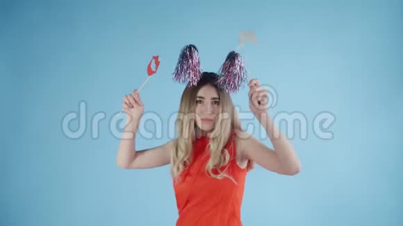 戴着派对帽的漂亮女孩正在蓝色背景下飘落的纸屑和气球下跳舞视频的预览图