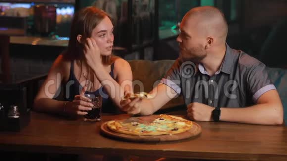 一对在酒吧吃不健康披萨的夫妇视频的预览图