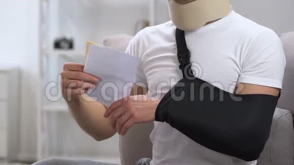 手臂吊带和颈项圈的休克男子看医疗账单支出视频的预览图