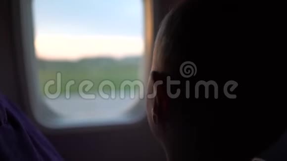 黎明时分妈妈带着一个孩子坐在一架飞机的窗户前视频的预览图