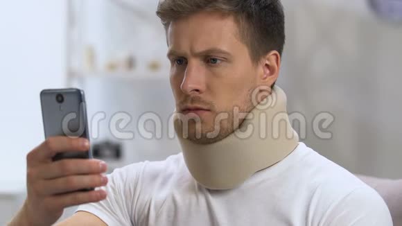 男性穿着颈圈手握电话突然感到脖子疼视频的预览图