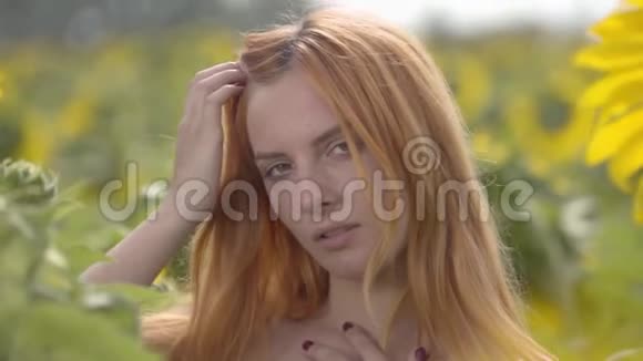 年轻自信的女人的肖像红头发绿眼睛看着相机抚摸着她站在上面的长发视频的预览图