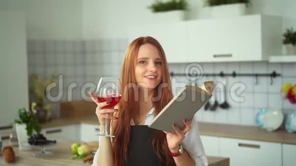 微笑的女人与酒杯阅读在厨房红头人类特写视频的预览图