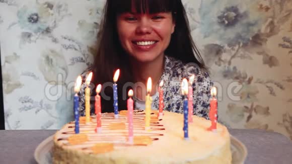 年轻女子在生日蛋糕上吹蜡烛庆祝周年视频的预览图