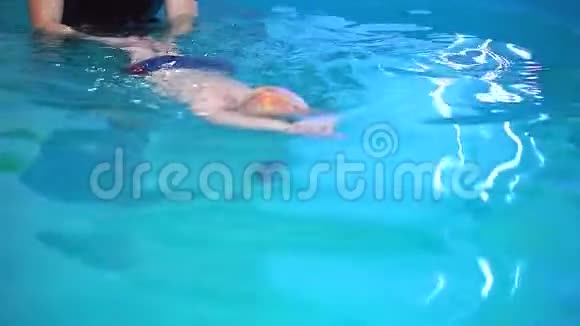 一个小男孩在游泳池里教练教他游泳特写视频的预览图