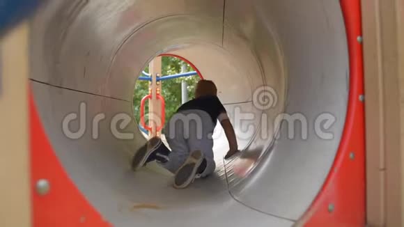 男孩在操场上的隧道里爬行视频的预览图