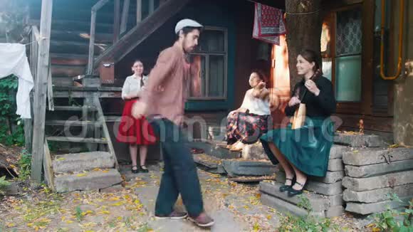 一个长胡子的男人在跳俄罗斯民族舞蹈女人坐在乡间别墅附近的楼梯一个女人在玩视频的预览图