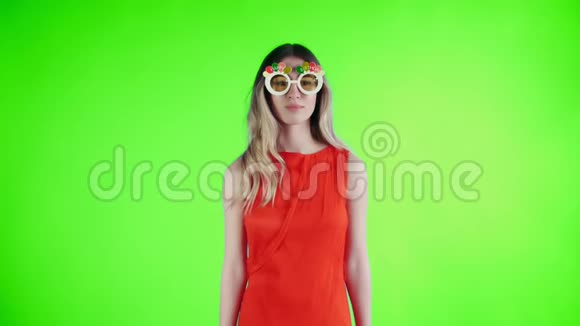 戴着滑稽眼镜的红衣女青年正在绿色屏幕上跳舞视频的预览图