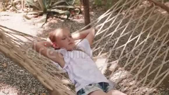 夏天躺在吊床上的快乐女孩暑假期间微笑的女孩在吊床上放松视频的预览图