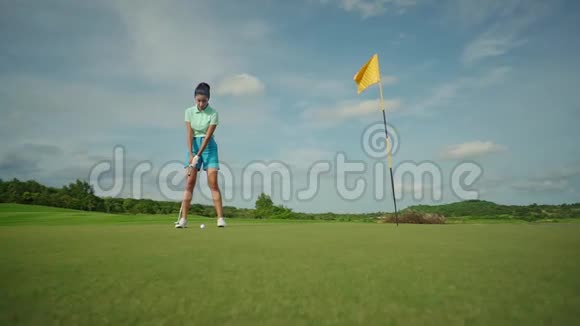 漂亮的球员女孩穿着蓝色短裤在练习驾驶场上打高尔夫非常活跃的娱乐活动视频的预览图