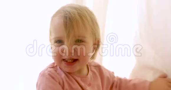 可爱的小女孩躲在窗帘后面视频的预览图