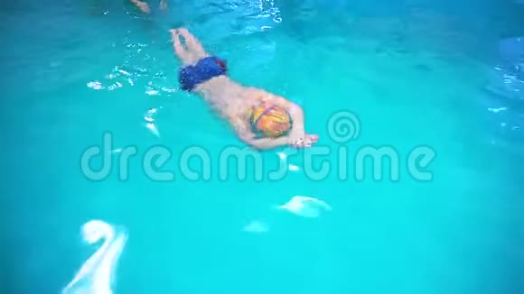 一个小男孩在游泳池里教练教他游泳俯视视频的预览图