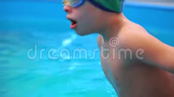 一个在游泳池里学游泳的小男孩特写他跳进水里视频的预览图