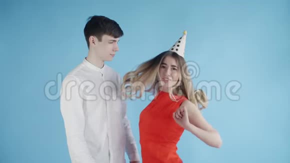 年轻的女人和男人在蓝色背景下在五颜六色的纸屑下跳舞视频的预览图