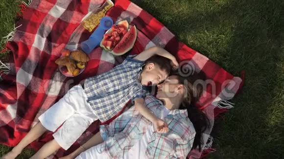妈妈和快乐的小儿子躺在草地上谈笑风生视频的预览图