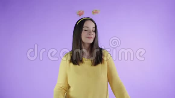 戴着滑稽帽子的漂亮年轻女人在紫色背景上用肥皂泡跳舞视频的预览图