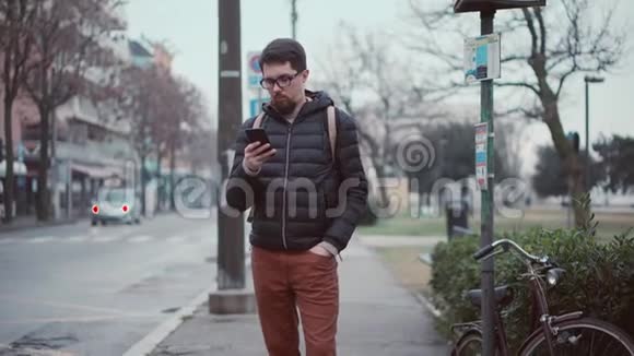 男人在车站等公共汽车用智能手机视频的预览图