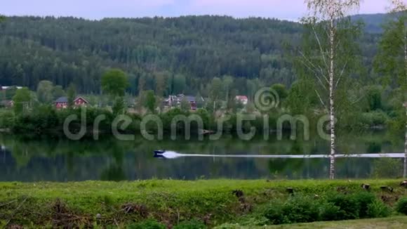 美丽的风景剪辑森林山和一个湖与一个速度机动船使180度转弯在阴天视频的预览图