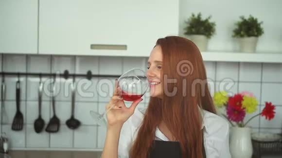 美丽的女人在家庭厨房品尝红酒红发人特写视频的预览图