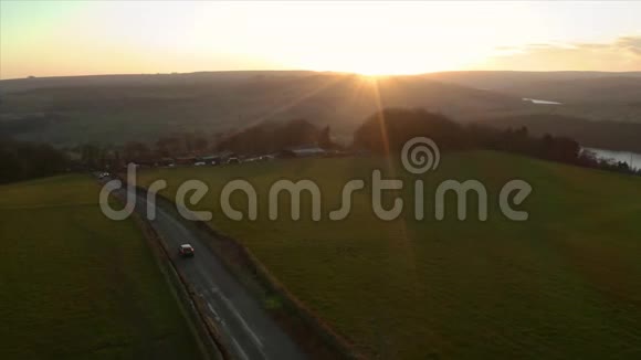 在一条狭窄的乡间小路上行驶的车辆周围旋转的空中镜头视频的预览图