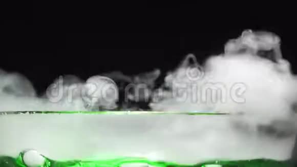 绿色液体沸腾释放烟雾在玻璃碗在黑色背景详细的特写视频的预览图