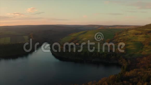 在英国金色的夕阳下空中飞过湖泊树木山丘和田野视频的预览图