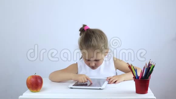 小女孩坐在书桌前在平板电脑上完成任务视频的预览图