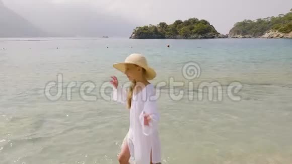穿着柳条帽在海滨散步的可爱少女视频的预览图