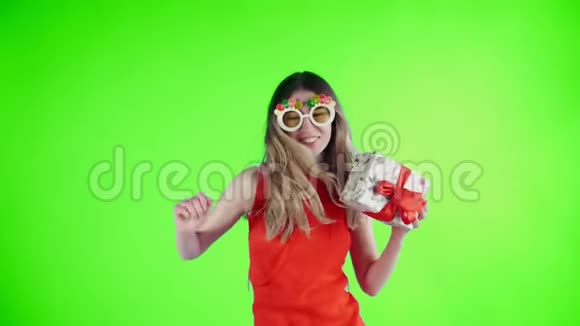 戴着滑稽眼镜的年轻女子手里拿着礼物在绿色的屏幕上跳舞视频的预览图