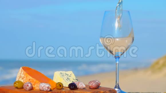 白葡萄酒倒入靠近奶酪橄榄的玻璃杯中视频的预览图