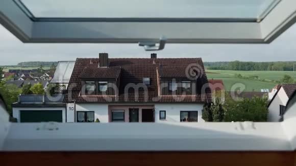 在阳光明媚的日子里摄像头从敞开的屋顶窗户向外照射在德国郊区的传统巴伐利亚住宅的美丽景色视频的预览图