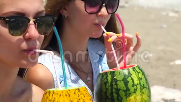 年轻漂亮的女孩戴着墨镜喝着新鲜的水果鸡尾酒视频的预览图