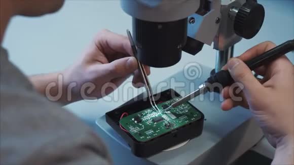 一位技术专家用电烙铁从专业相机上修复充电器微电路视频的预览图