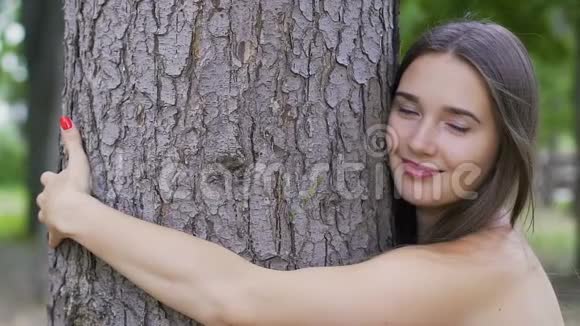 微笑的女人拥抱一棵树微笑生活快乐热爱自然环境保护视频的预览图