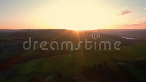 空中镜头看着夕阳飞过郁郁葱葱的草地视频的预览图