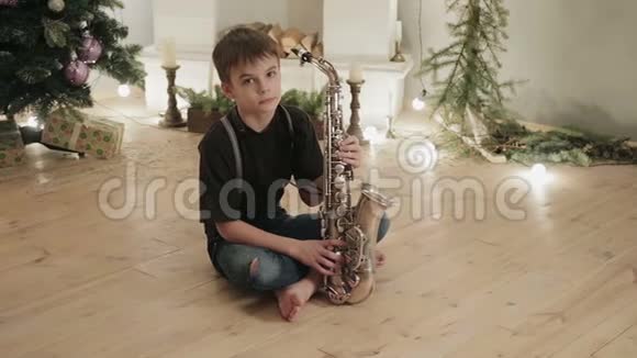 年轻的音乐家萨克斯演奏家坐在房子的地板上背景是圣诞节的装饰品视频的预览图