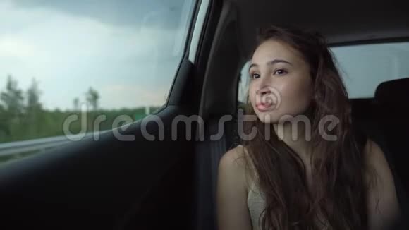 年轻的女乘客坐在车里看着车窗视频的预览图