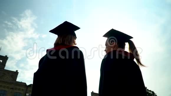 后景两个快乐的学生在壁炉前庆祝他们的毕业在大学大楼前新毕业视频的预览图