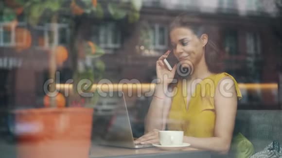 女孩子在午休时用手机和笔记本电脑坐在咖啡厅视频的预览图