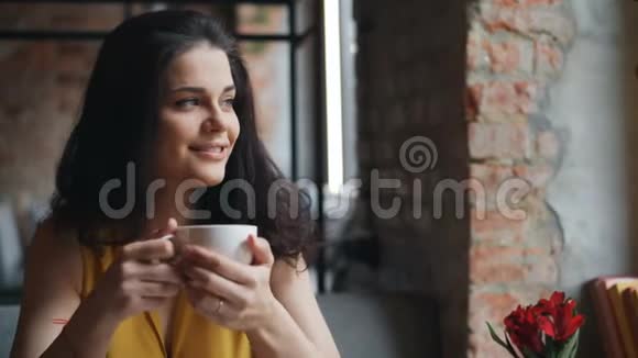 快乐的女孩在咖啡馆喝茶捧着杯子微笑着享受饮料视频的预览图