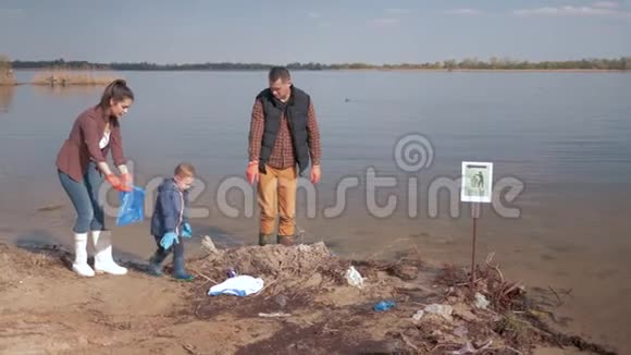环境保护男孩帮助家庭志愿者积极分子清理污染的河滩塑料垃圾和视频的预览图